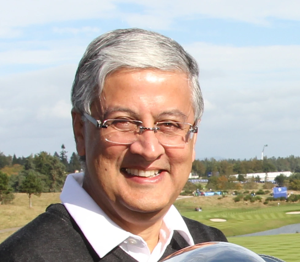 Sir Ivan Menezes smiling outdoors at an event