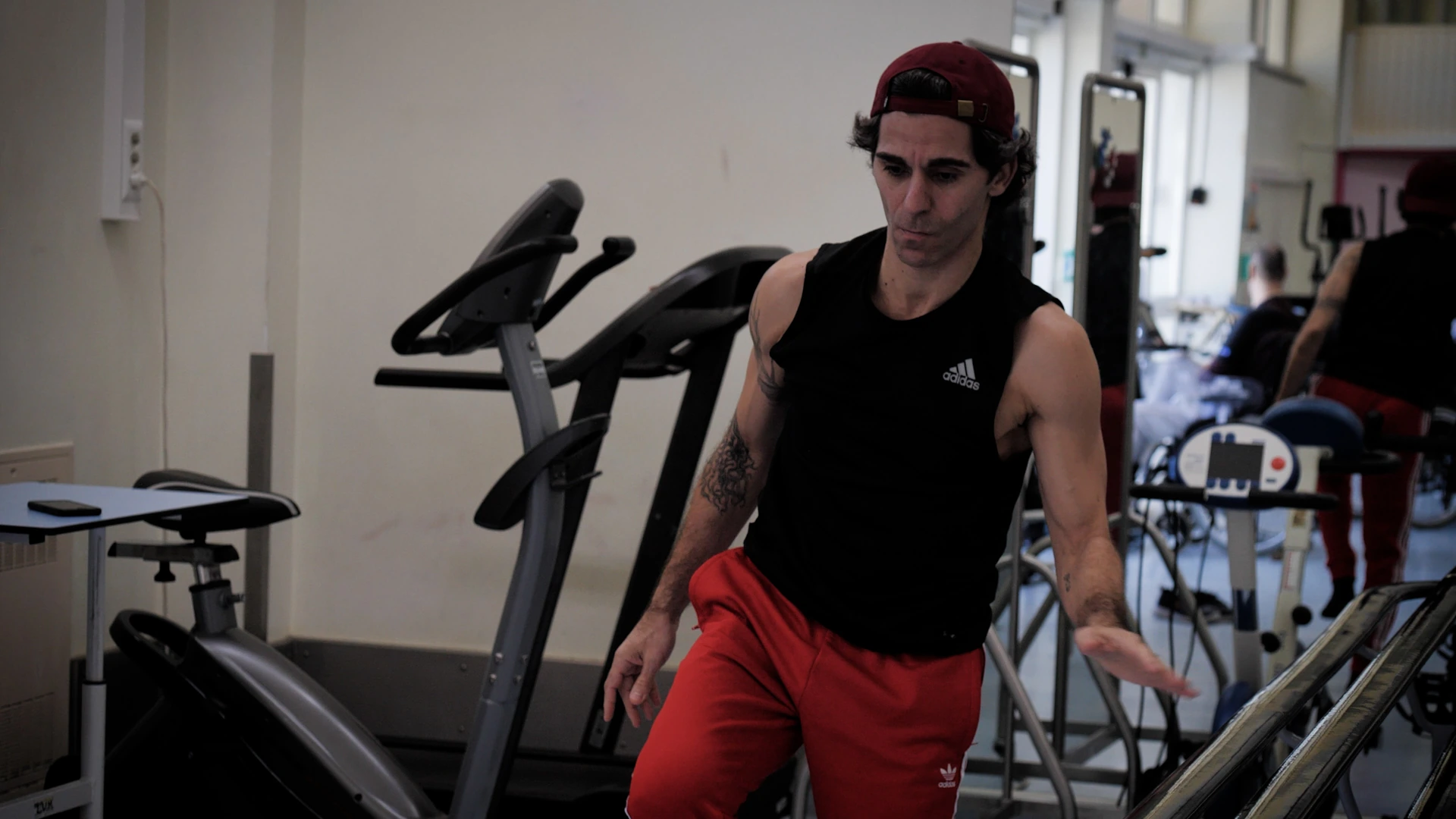 Daniel Cardoso in a dance studio or rehearsal setting, wearing a black sleeveless top and red pants, captured in a docum