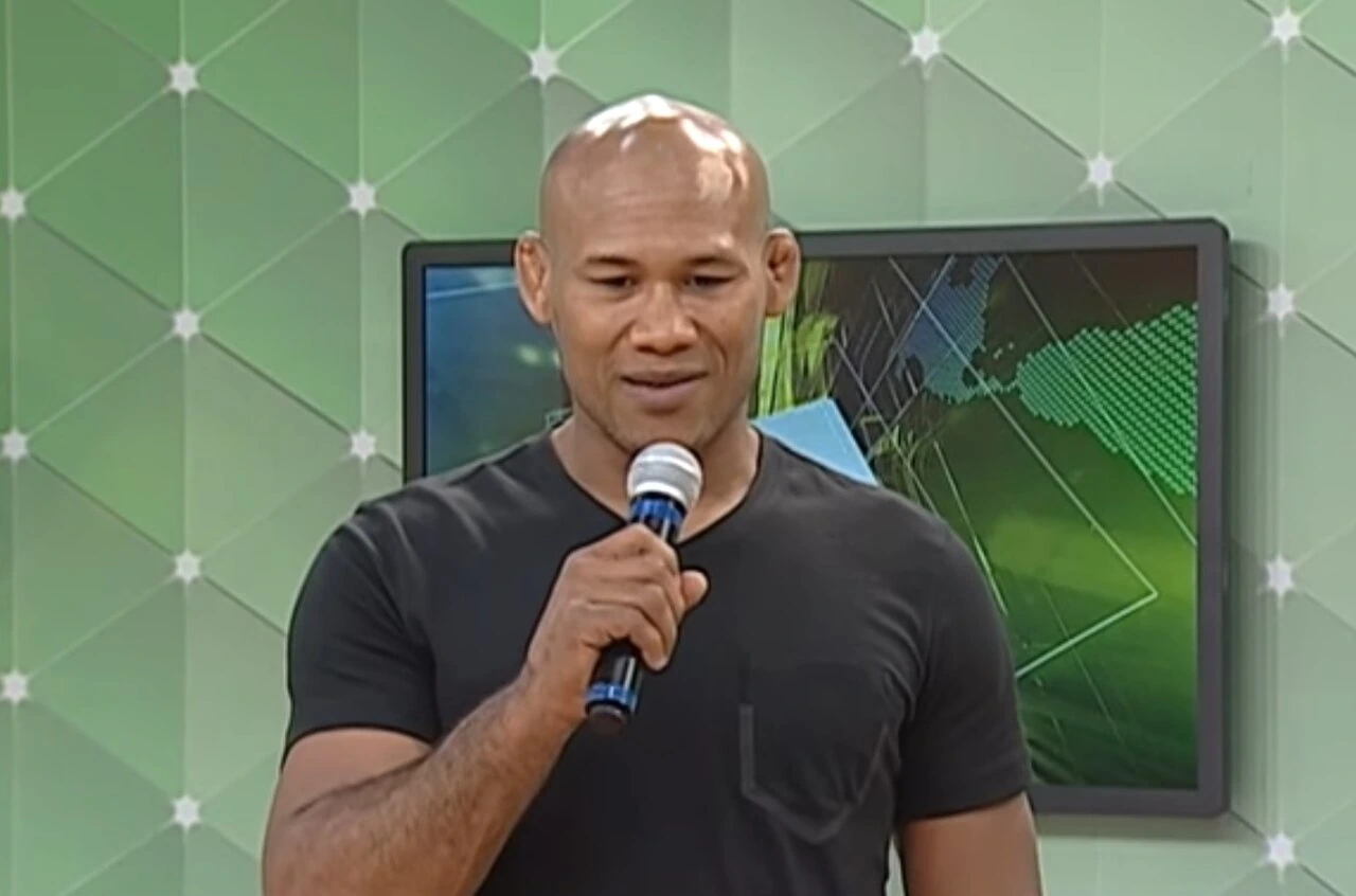 Ronaldo 'Jacaré' Souza speaking into a microphone in a studio setting