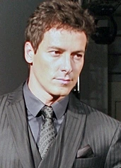 Rodrigo Faro in a suit and tie posing for a portrait.