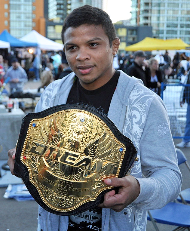 Bibiano Fernandes holding a championship belt outdoors at an event